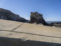 the stone walkway is leading to the beach and water's edge of a rocky coastline