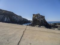 the stone walkway is leading to the beach and water's edge of a rocky coastline