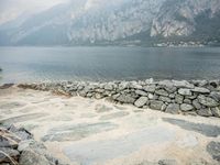 stone walkway beside the water with mountains and rocks in the background on a cloudy day