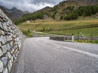 a small stone wall near a road and mountain range in the distance in front of it