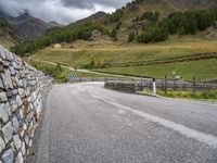 a small stone wall near a road and mountain range in the distance in front of it