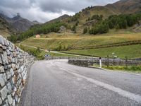 a small stone wall near a road and mountain range in the distance in front of it