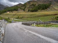 a small stone wall near a road and mountain range in the distance in front of it