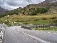 a small stone wall near a road and mountain range in the distance in front of it