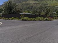 a stop sign sitting at the end of a paved street in front of hills and greenery