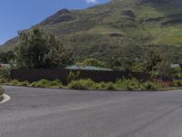 a stop sign sitting at the end of a paved street in front of hills and greenery