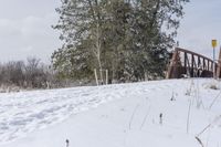 an orange sign that reads, stop at the end of a bridge on snow covered ground