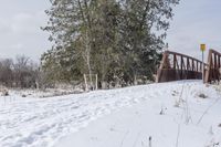 an orange sign that reads, stop at the end of a bridge on snow covered ground