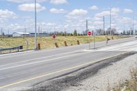 several stop signs are on the roadside by the highway side of the road in this image