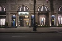 an outside shot of a store front in a town with street lights on either side