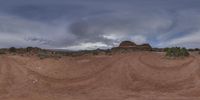 an image of a sky over the ground and rocks on a hill under stormy skies