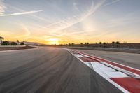 a photo of a dirt race track with sun setting in the distance of the track