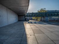 a skateboarder riding on a cement ramp next to a city street under a bridge