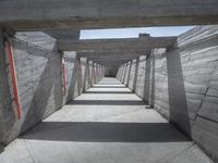 a long hallway lined with concrete walls and windows and light posts and beams above it