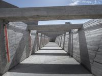 a long hallway lined with concrete walls and windows and light posts and beams above it