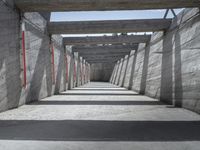 a long hallway lined with concrete walls and windows and light posts and beams above it