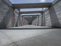 a long hallway lined with concrete walls and windows and light posts and beams above it