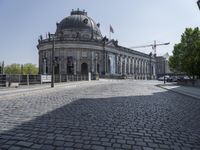 an open street leading into a very big building next to a city bridge with lots of traffic