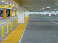 a yellow car park in the middle of an underground parking garage with concrete and yellow poles