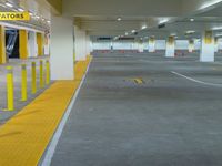 a yellow car park in the middle of an underground parking garage with concrete and yellow poles