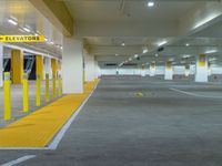 a yellow car park in the middle of an underground parking garage with concrete and yellow poles
