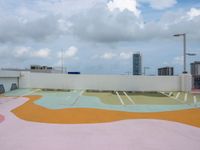 a roof with an open air park with a colorful mural on the pavement below some building