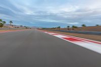 a photo of a dirt race track with sun setting in the distance of the track