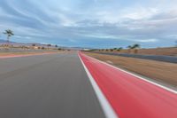 a photo of a dirt race track with sun setting in the distance of the track