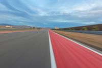 a photo of a dirt race track with sun setting in the distance of the track