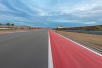 a photo of a dirt race track with sun setting in the distance of the track