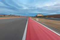 a photo of a dirt race track with sun setting in the distance of the track