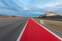 a photo of a dirt race track with sun setting in the distance of the track