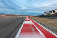 a photo of a dirt race track with sun setting in the distance of the track