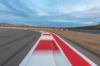 a photo of a dirt race track with sun setting in the distance of the track