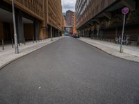 a long narrow road in the city with no traffic on it's sides, lined with buildings and street signs