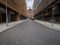 a long narrow road in the city with no traffic on it's sides, lined with buildings and street signs