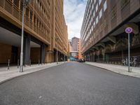 a long narrow road in the city with no traffic on it's sides, lined with buildings and street signs