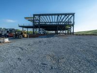 a picture of a building being built on a field near a forest in the background