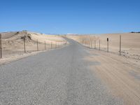 a paved beach with a fence in front of it and the ocean in the distance