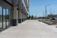 concrete sidewalk in the middle of city with vehicles parked nearby on the side walk on a sunny day