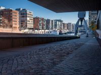 the walkway is made from brick bricks in this view of tall buildings and a waterway