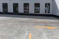 a yellow painted line of parking spaces on top of a building with doors and windows