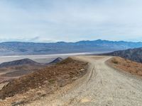 gravel road and mountains with a view of lake mead below on a cloudy day in the california foothills