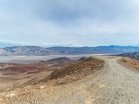 gravel road and mountains with a view of lake mead below on a cloudy day in the california foothills