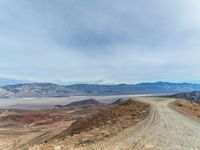 gravel road and mountains with a view of lake mead below on a cloudy day in the california foothills