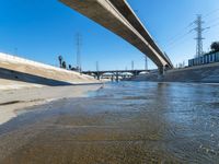 a large bridge over a creek next to power lines and water filled with floodwater