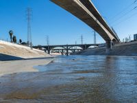 a large bridge over a creek next to power lines and water filled with floodwater