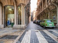 parked cars and some people walking on a street by some buildings, there are shops