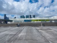 the sky is full of fluffy clouds and buildings in the background with an empty parking lot