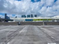 the sky is full of fluffy clouds and buildings in the background with an empty parking lot